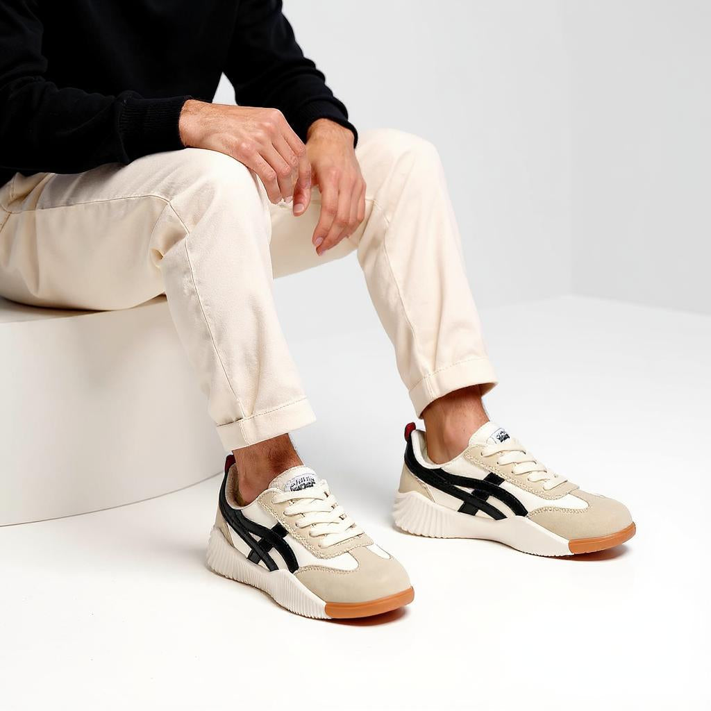 Frau in weißem T-Shirt und blauer Jeans trägt bequeme Onitsuka Tiger Sneaker aus beigem Wildleder mit schwarzen Streifen – entlastet den Rücken, lindert Fußschmerzen, ideal bei Fersensporn, Achillessehnenentzündung und Schienbeinschmerzen