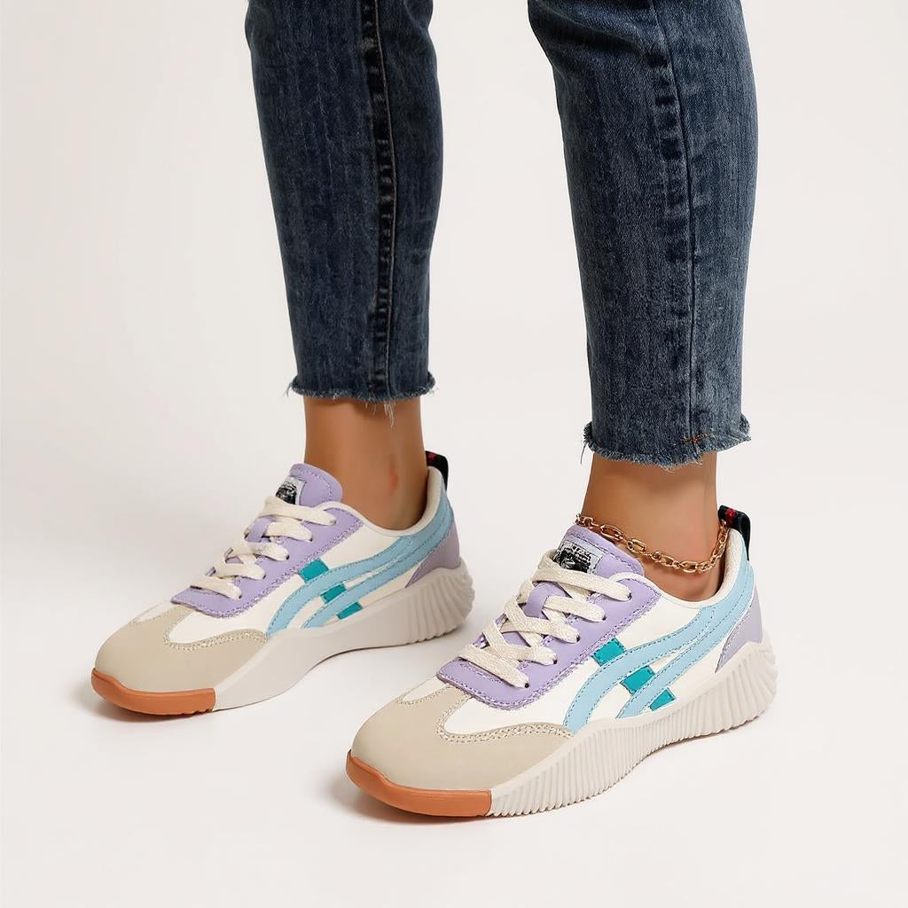 Damen tragen Onitsuka Tiger Sneaker aus Wildleder und Mesh in Beige, Weiß, Flieder und Hellblau mit gezackter Sohle, kombiniert mit dunkelblauen Jeans – modische und bequeme Freizeitschuhe